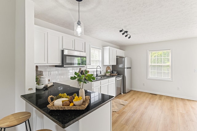 1503 Cassell Ln, Bedford, VA 24523 - kitchen featuring stainless steel appliances, a sink, light wood-style floors, backsplash, and a textured ceiling