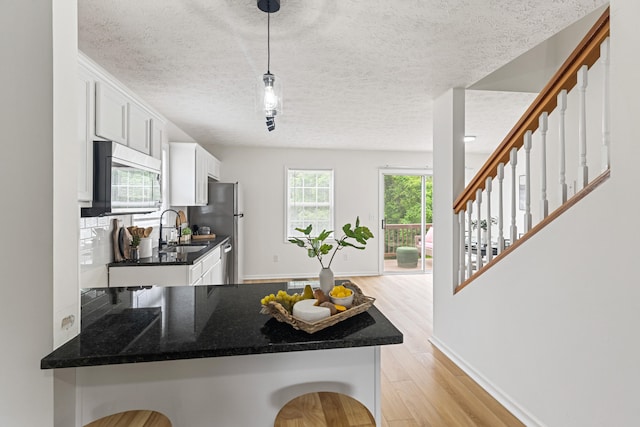 1503 Cassell Ln, Bedford, VA 24523 - kitchen with a textured ceiling, a sink, light wood-type flooring, white cabinets, and baseboards