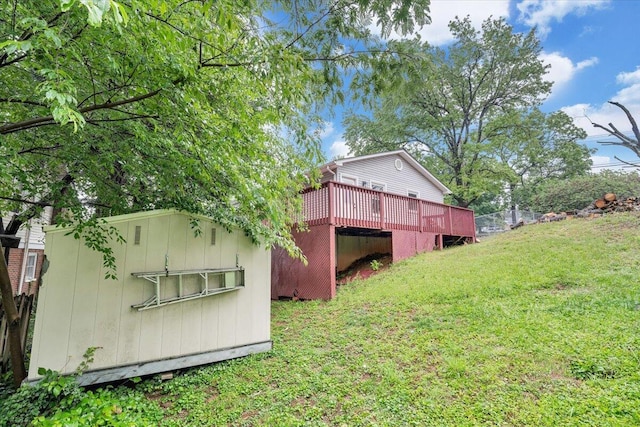 back of house featuring a yard, a wooden deck, and an outbuilding