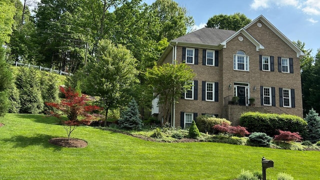 colonial-style house with a front yard and brick siding