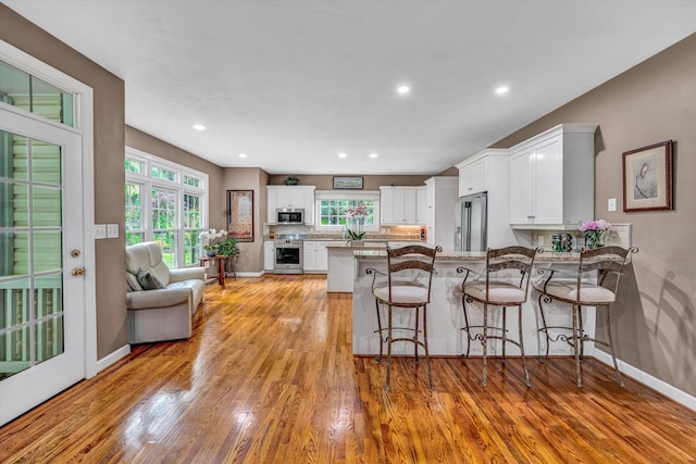 kitchen featuring stainless steel appliances, baseboards, white cabinets, a peninsula, and recessed lighting