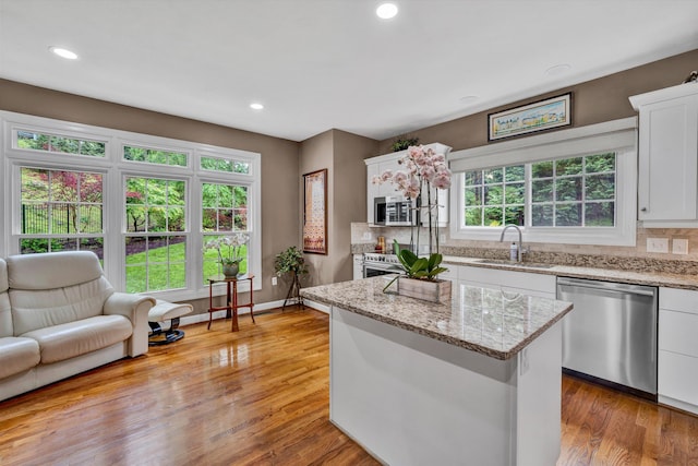 kitchen with stainless steel appliances, white cabinets, tasteful backsplash, a kitchen island, and recessed lighting