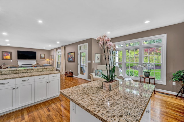 kitchen featuring open floor plan, light wood-style floors, recessed lighting, white cabinets, and light stone counters