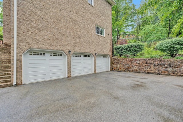garage featuring driveway and fence