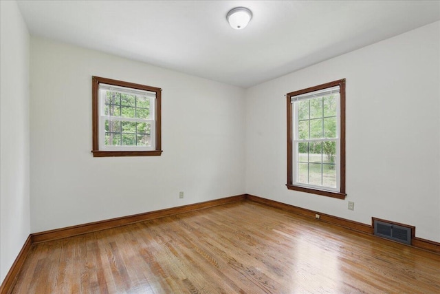 unfurnished room featuring healthy amount of natural light, wood finished floors, and baseboards
