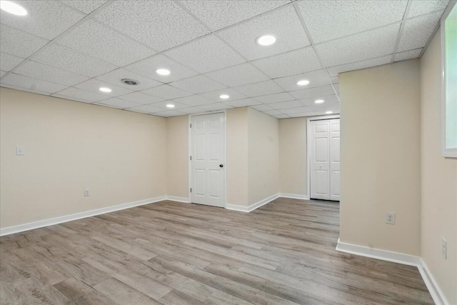 finished below grade area with wood finished floors, baseboards, recessed lighting, and a paneled ceiling