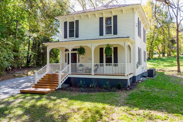 view of front of home with covered porch, central AC unit, a standing seam roof, metal roof, and a front lawn
