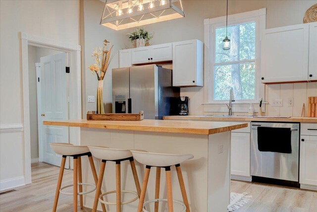 kitchen featuring appliances with stainless steel finishes, a sink, wood counters, light wood-type flooring, and white cabinets
