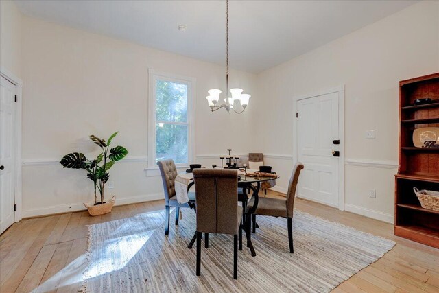 dining space featuring light wood finished floors, a chandelier, and baseboards