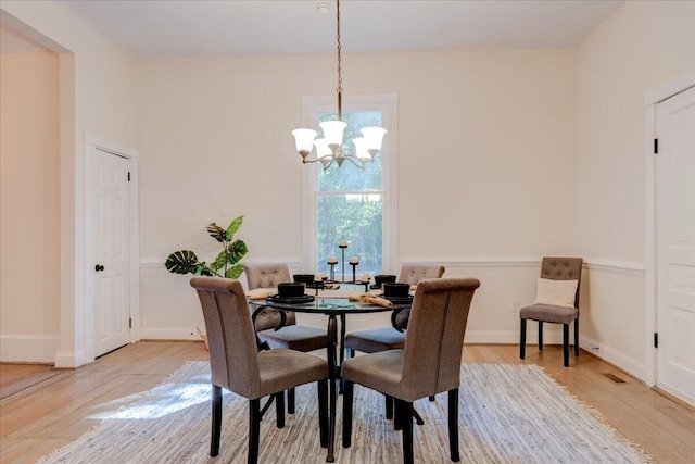 dining area with light wood-style floors, a chandelier, and baseboards