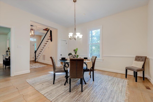 dining room featuring a chandelier, stairway, light wood-type flooring, and baseboards