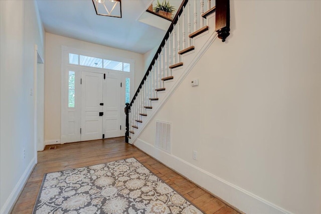 foyer entrance featuring stairs, wood finished floors, and baseboards