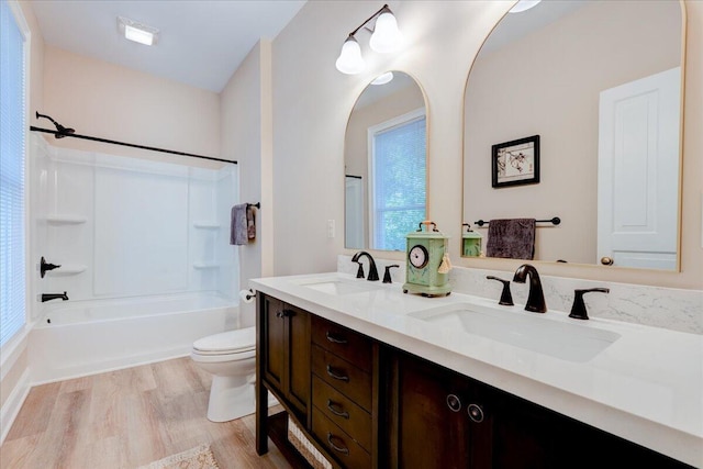 bathroom featuring wood finished floors, toilet, shower / bath combination, and double vanity