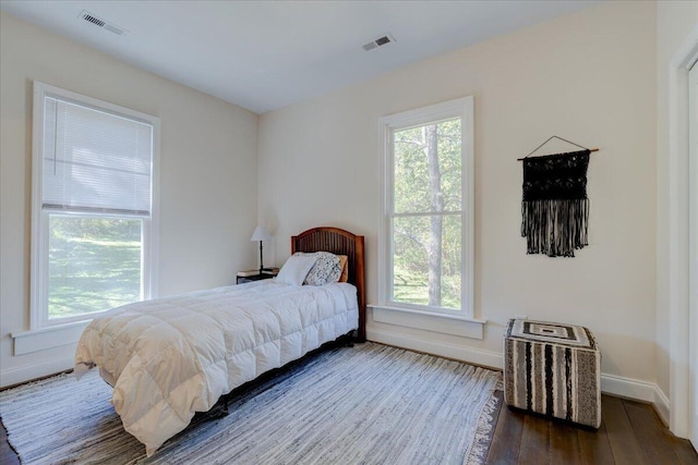 bedroom featuring multiple windows, baseboards, and wood finished floors
