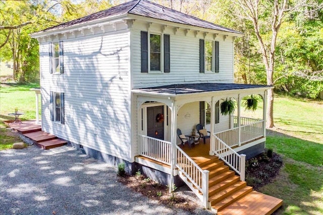 view of front of house with covered porch, a front lawn, and roof with shingles