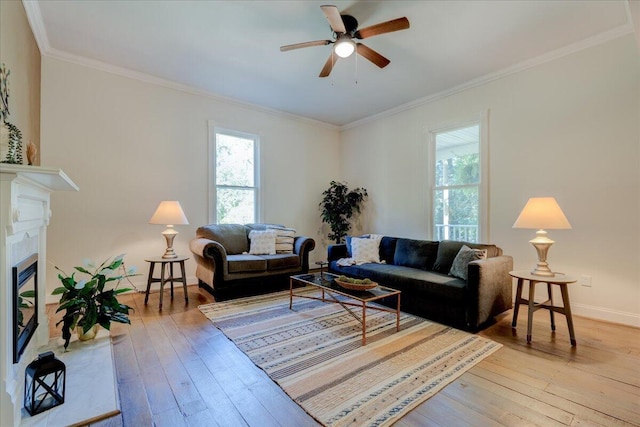 living room with plenty of natural light, light wood-style floors, ceiling fan, and ornamental molding