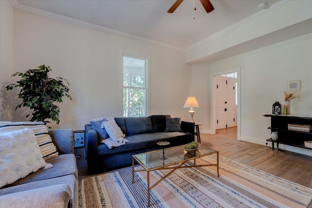 living area featuring light wood-style floors, ceiling fan, ornamental molding, and baseboards