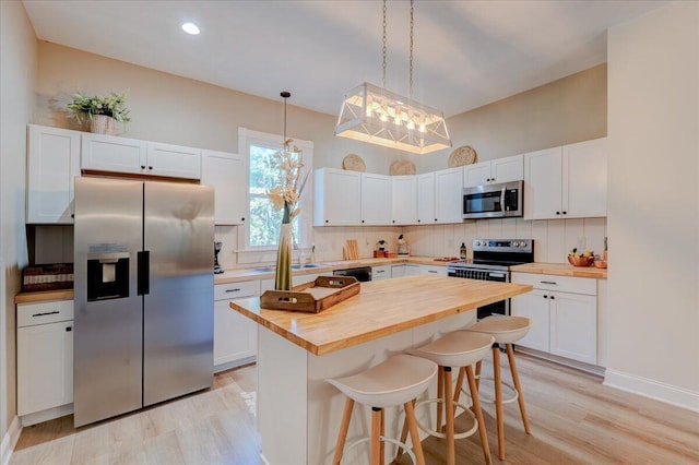 kitchen featuring stainless steel appliances, butcher block counters, light wood-type flooring, tasteful backsplash, and recessed lighting
