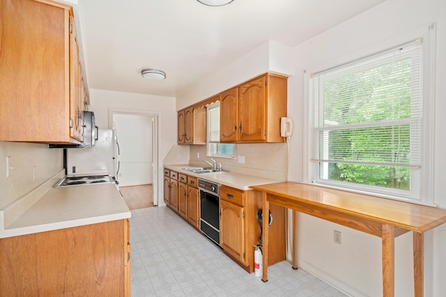 kitchen featuring dishwasher, a sink, light countertops, light flooring, and brown cabinets