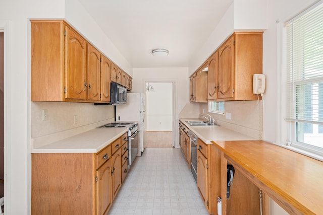 kitchen with a sink, light floors, stainless steel appliances, and light countertops