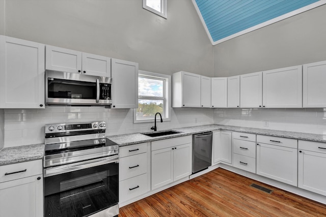 475 S Main St, Rocky Mount, VA 24151 - kitchen with stainless steel appliances, a sink, a towering ceiling, white cabinetry, and backsplash