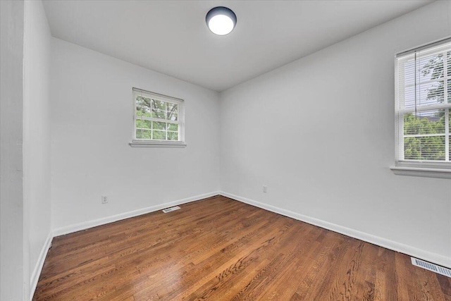 spare room featuring baseboards and dark wood-style flooring