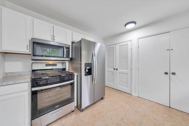 kitchen with stainless steel appliances, light countertops, white cabinetry, and light tile patterned floors