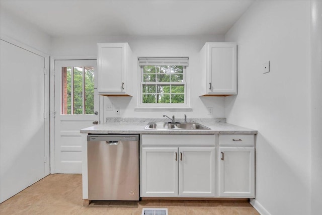 kitchen with stainless steel dishwasher, a sink, white cabinets, light countertops, and light tile patterned floors