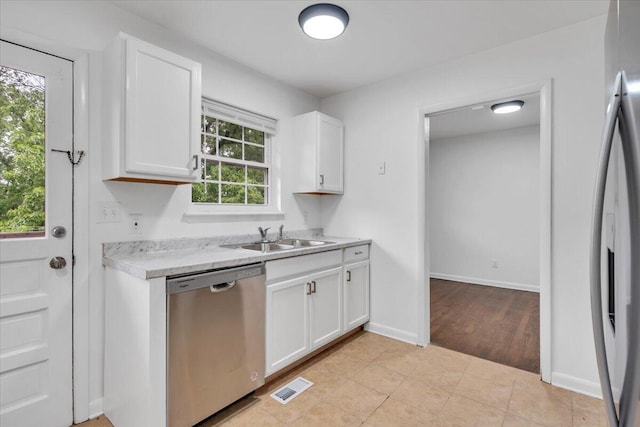 kitchen featuring stainless steel dishwasher, a sink, light countertops, fridge with ice dispenser, and white cabinetry