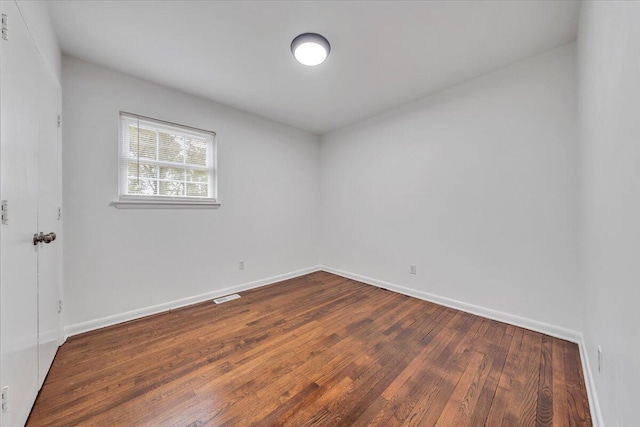 unfurnished room with dark wood-type flooring and baseboards