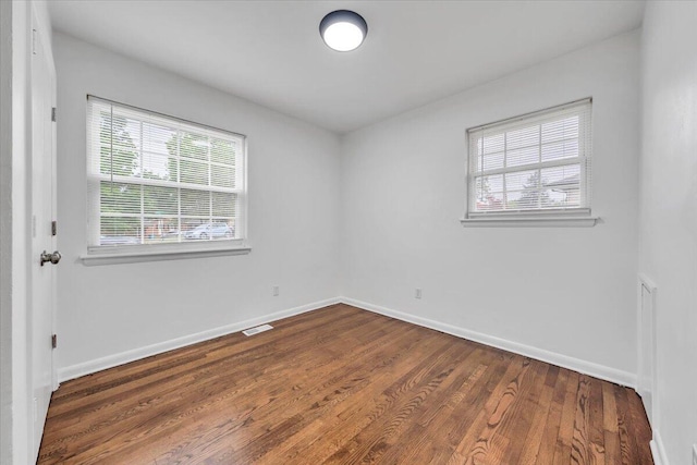 unfurnished room with plenty of natural light, wood finished floors, and baseboards
