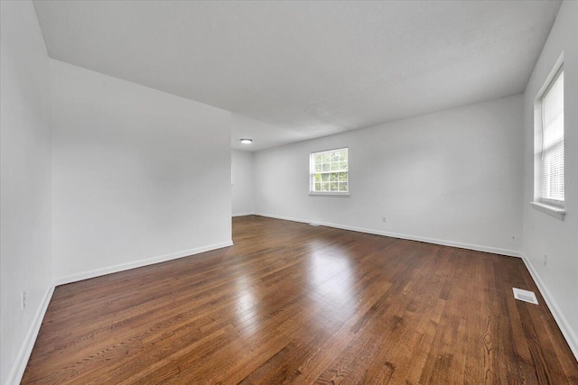 spare room with dark wood-style flooring and baseboards