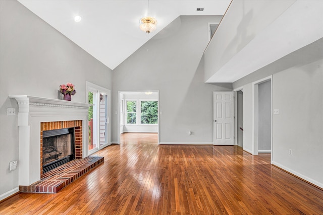 unfurnished living room featuring wood-type flooring, a brick fireplace, high vaulted ceiling, and baseboards