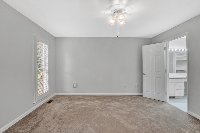 carpeted empty room with ceiling fan and baseboards