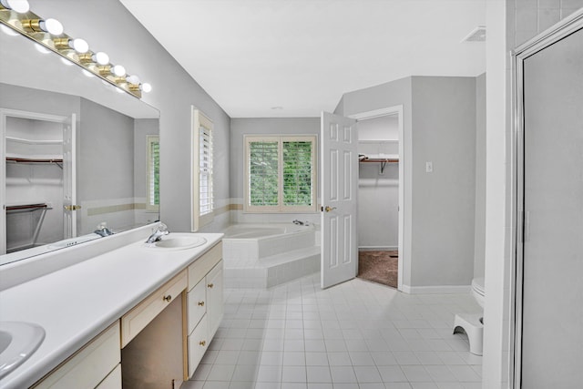 full bath with tile patterned floors, a garden tub, double vanity, toilet, and a spacious closet