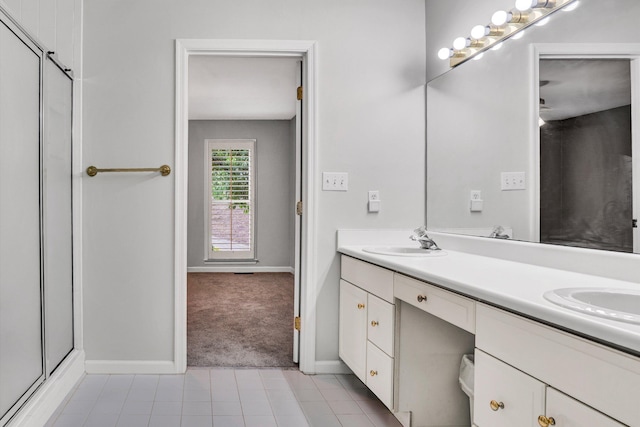 full bath featuring baseboards, double vanity, an enclosed shower, and tile patterned floors