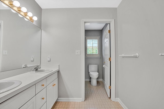 full bath featuring toilet, baseboards, and double vanity