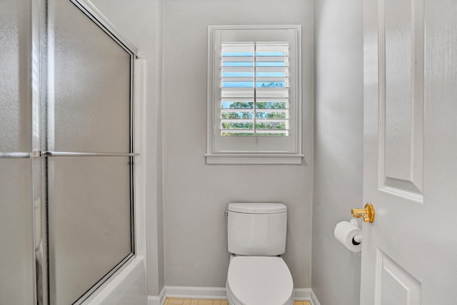 full bathroom featuring baseboards, toilet, and combined bath / shower with glass door