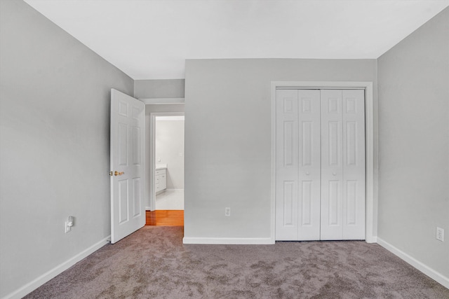 unfurnished bedroom with carpet floors, baseboards, and a closet