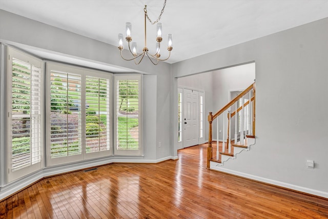 entryway with hardwood / wood-style flooring, a chandelier, baseboards, and stairway