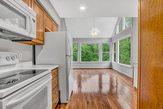 kitchen with white appliances, brown cabinets, light countertops, healthy amount of natural light, and vaulted ceiling