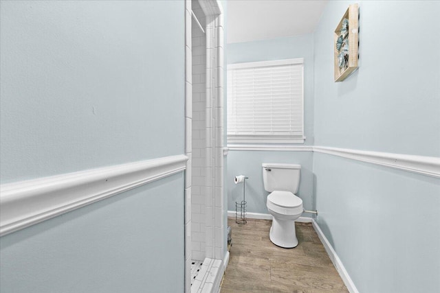 full bathroom featuring toilet, wood finished floors, a shower stall, and baseboards