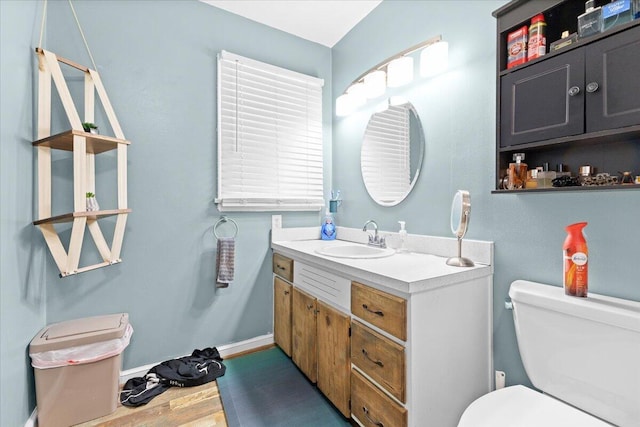 bathroom with toilet, vanity, and wood finished floors