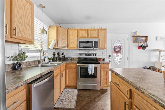 kitchen with stainless steel appliances, a sink, tasteful backsplash, and dark wood-type flooring
