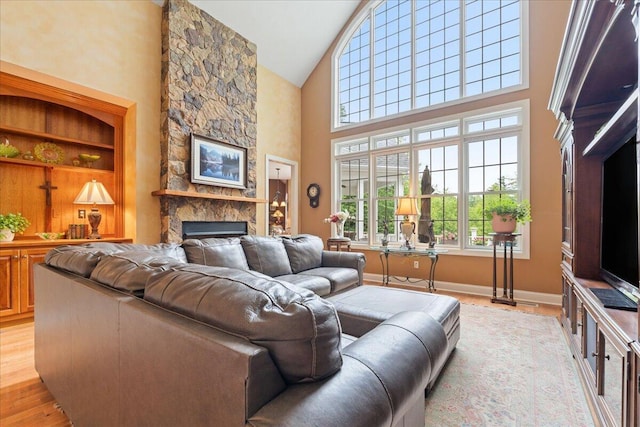 living room with high vaulted ceiling, a fireplace, and light wood-style flooring