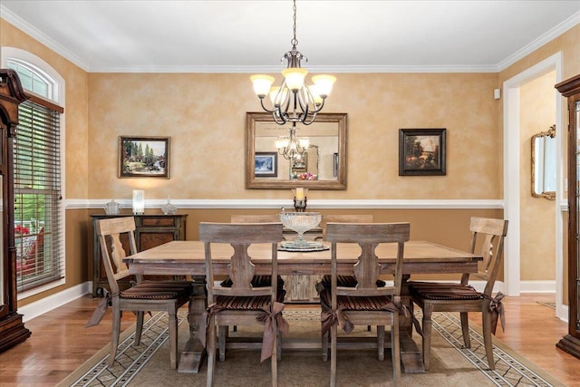 dining space featuring a chandelier, wood finished floors, ornamental molding, and baseboards