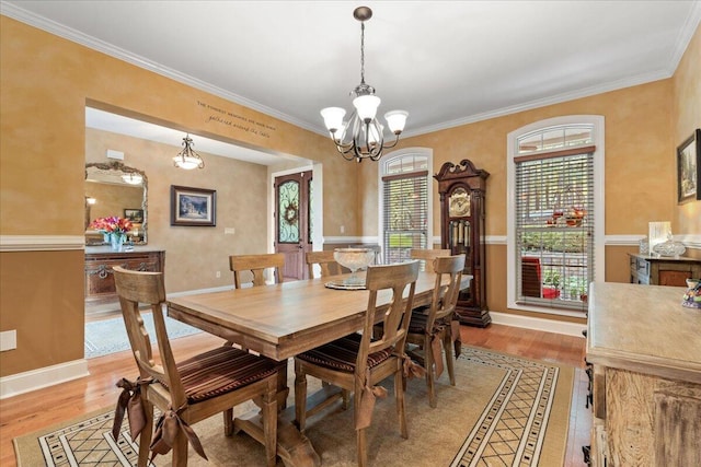 dining area featuring a chandelier, light wood-style floors, baseboards, and crown molding