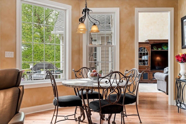 dining area with light wood-type flooring, healthy amount of natural light, and baseboards