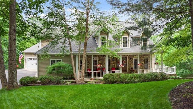 back of house with covered porch, an attached garage, a lawn, concrete driveway, and stone siding