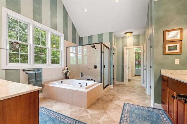 bathroom featuring vanity, a shower stall, a garden tub, high vaulted ceiling, and baseboards